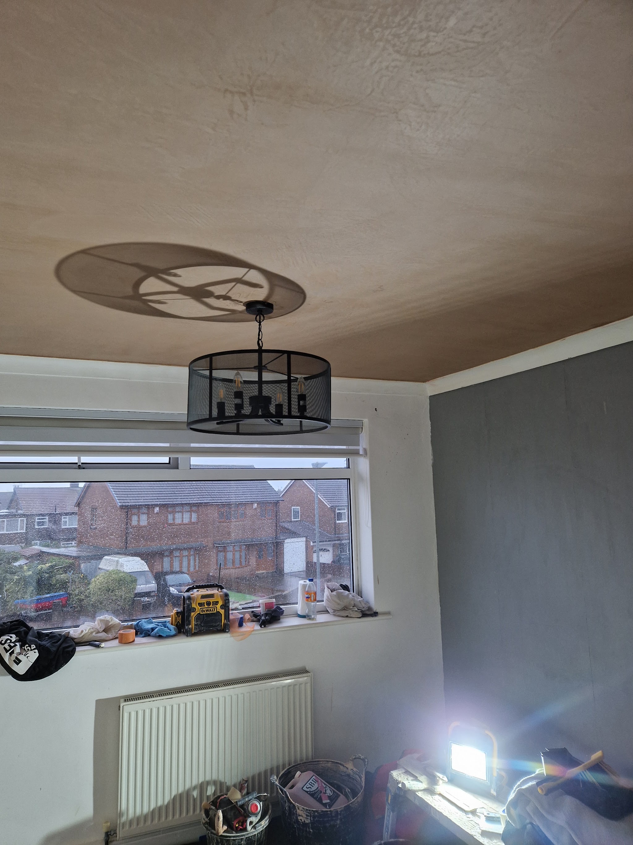 Room freshly plastered, walls and ceiling finished, tools resting on the window sill