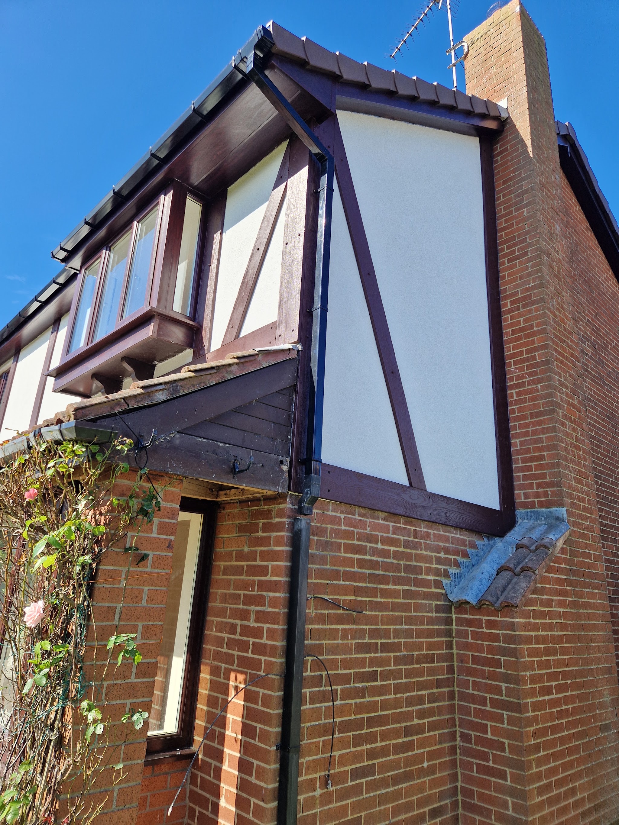 Mock-Tudor gable panels rendered fresh white on a brick house